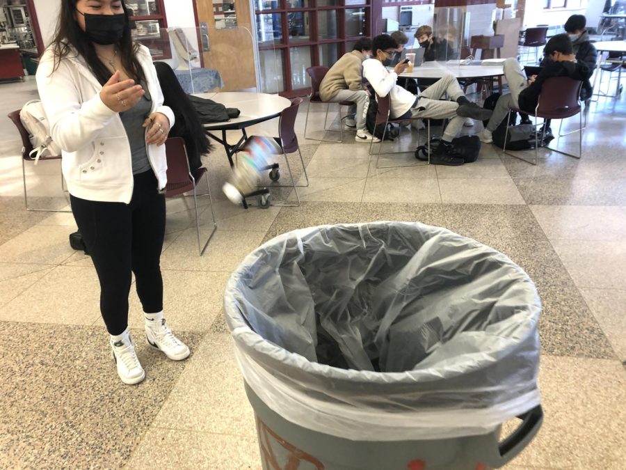 A WHS student throws a plastic bottle into a trashcan 