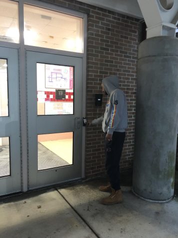 WHS senior Alcapone Pujouls unlocking the main entrance with an ID access badge.
