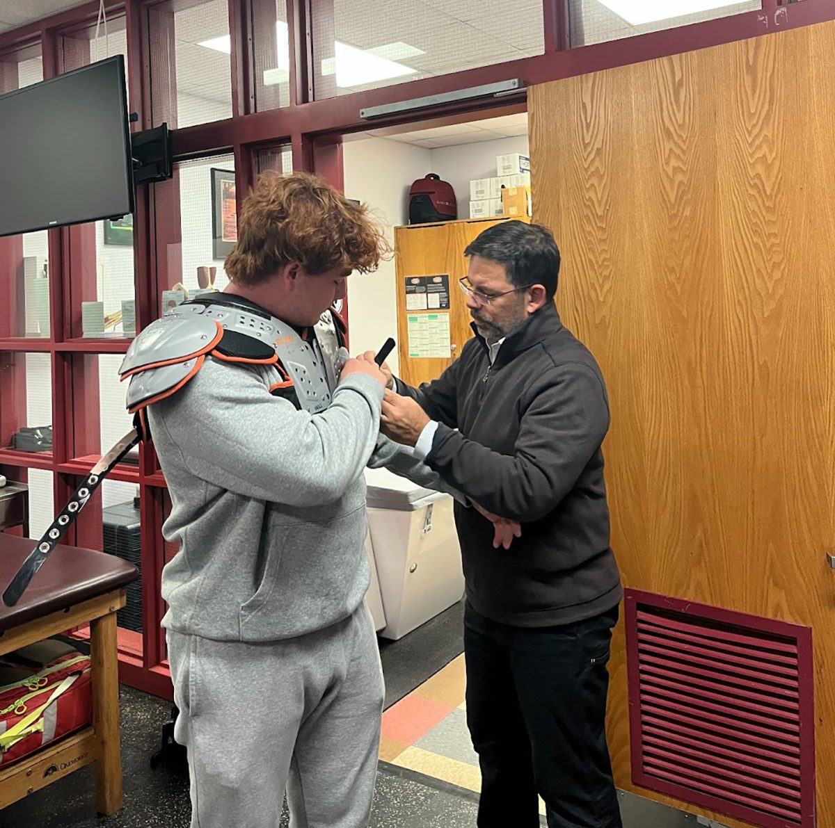 Rizza helps athlete Owain Hawks prior to football practice				                        