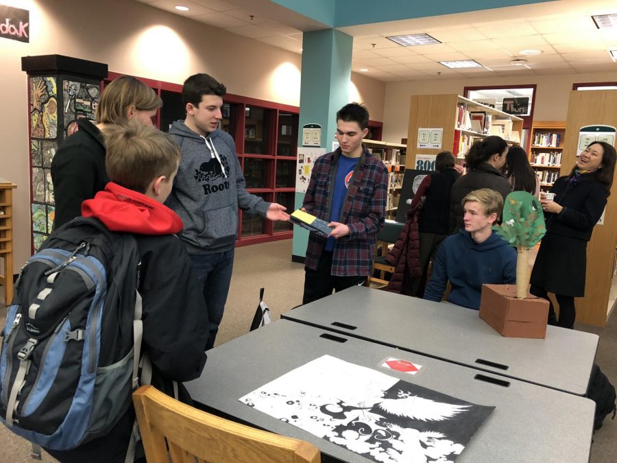 Carter Sullivan, Samuel Berbeco, and Raymond Grocela at a table with a crowd. 
