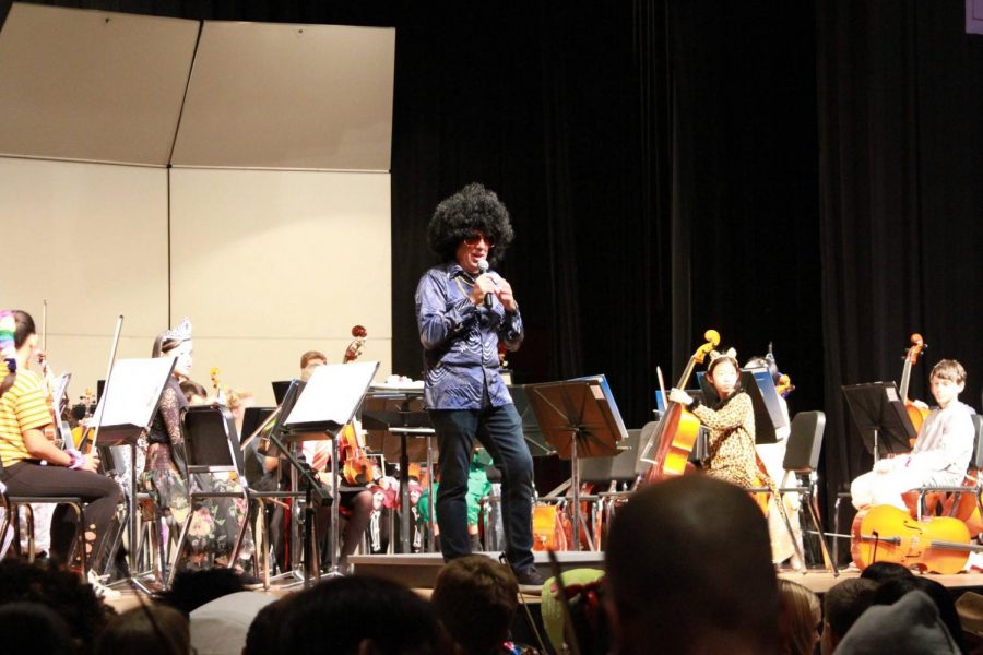 Music department head Christopher Memoli opens the concert with a speech of thanks in a groovy Halloween costume.