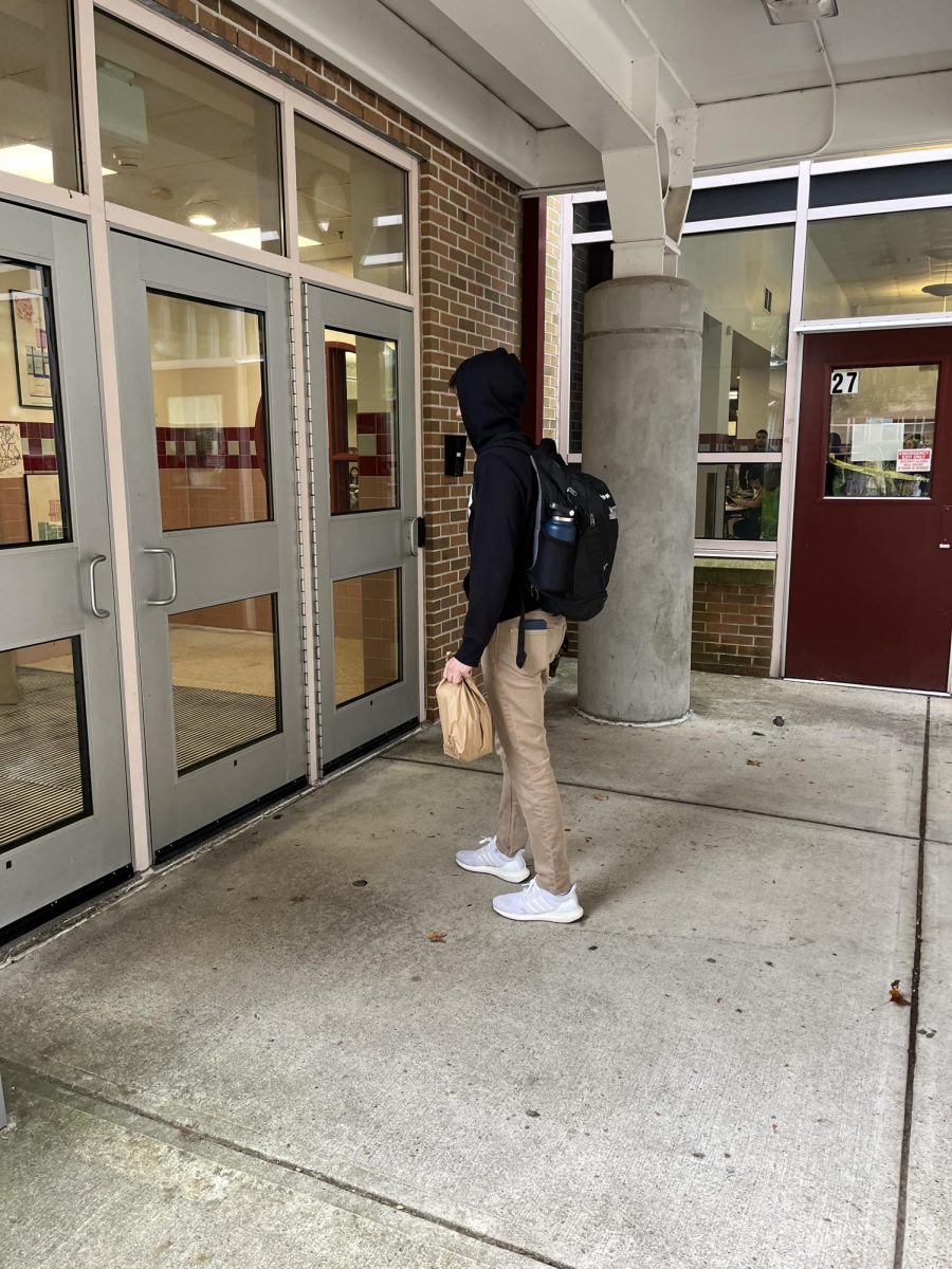 Student walks into school after recieving their food delivery.                     